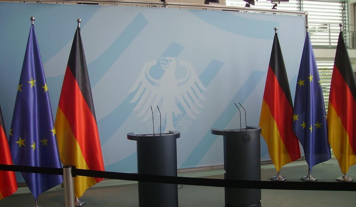 На сцене стоят флаги Германии и Евросоюза-RU