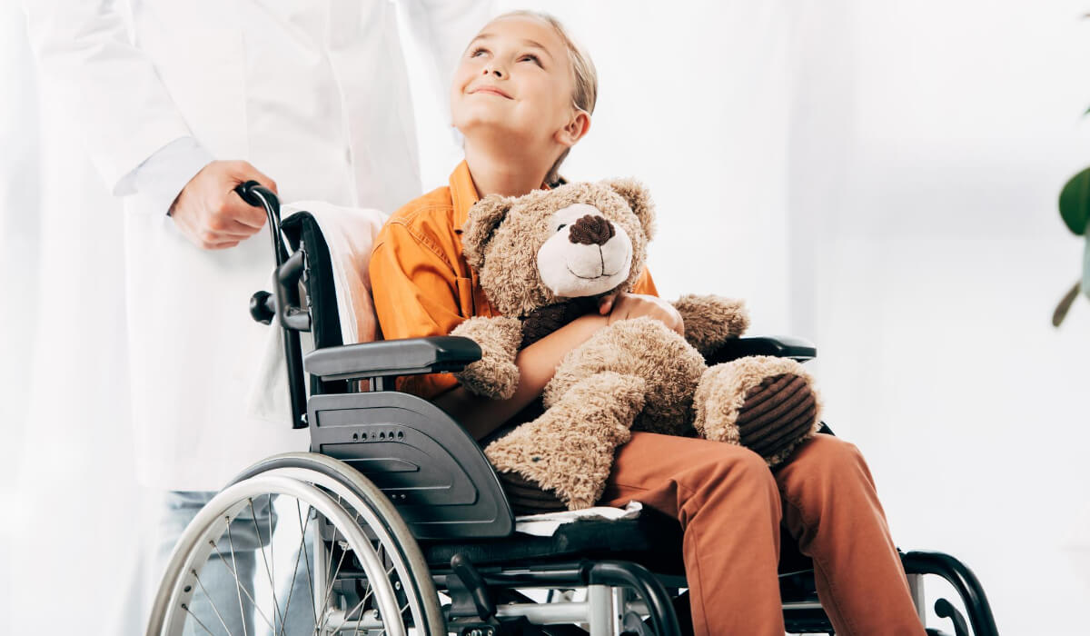 Kind im Rollstuhl hält Teddybär