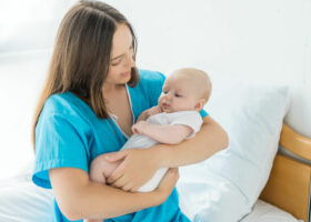 Женщина держит ребенка на руках в немецкой больнице после родов