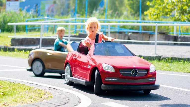 Дети катаются на машинках в парке развлечений 