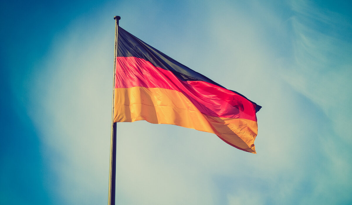 На фоне неба развевается немецкий флаг. Ru