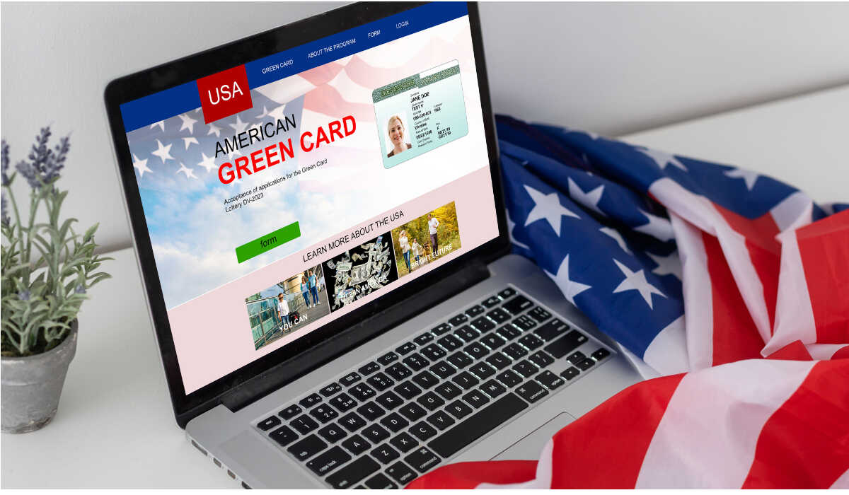 На столе флаг Америки и ноутбук с надписью на экране Green Card-RU
