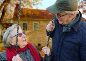 Ein älteres Ehepaar schaukelt genüsslich auf der Schaukel und genießt den sonnigen Tag im Park.