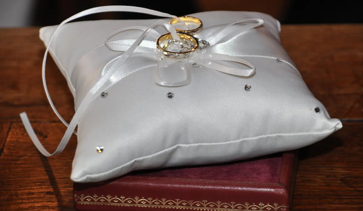 Обручальные кольца лежат на белой маленькой подушке
